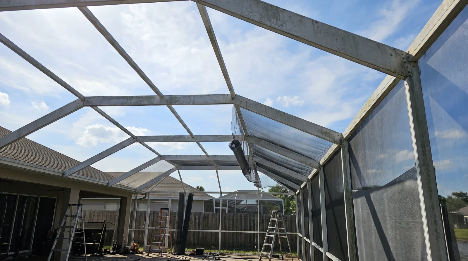 The aluminum frame of a Florida pool cage enclosure with screening partly installed